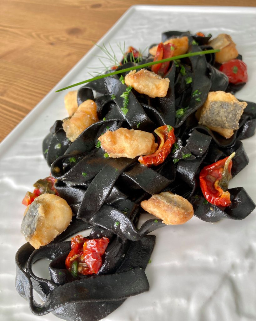 tagliatelle nere di nostra produzione con branzino croccante il suo fondo e pomodorini confit.