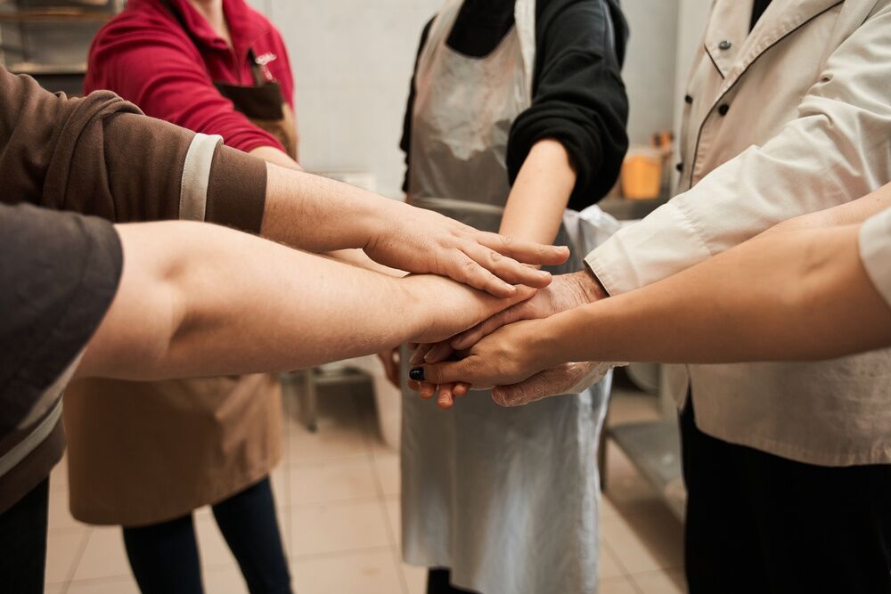 Eventi Business bakery team keeping hands together as a symbol of unity while working together